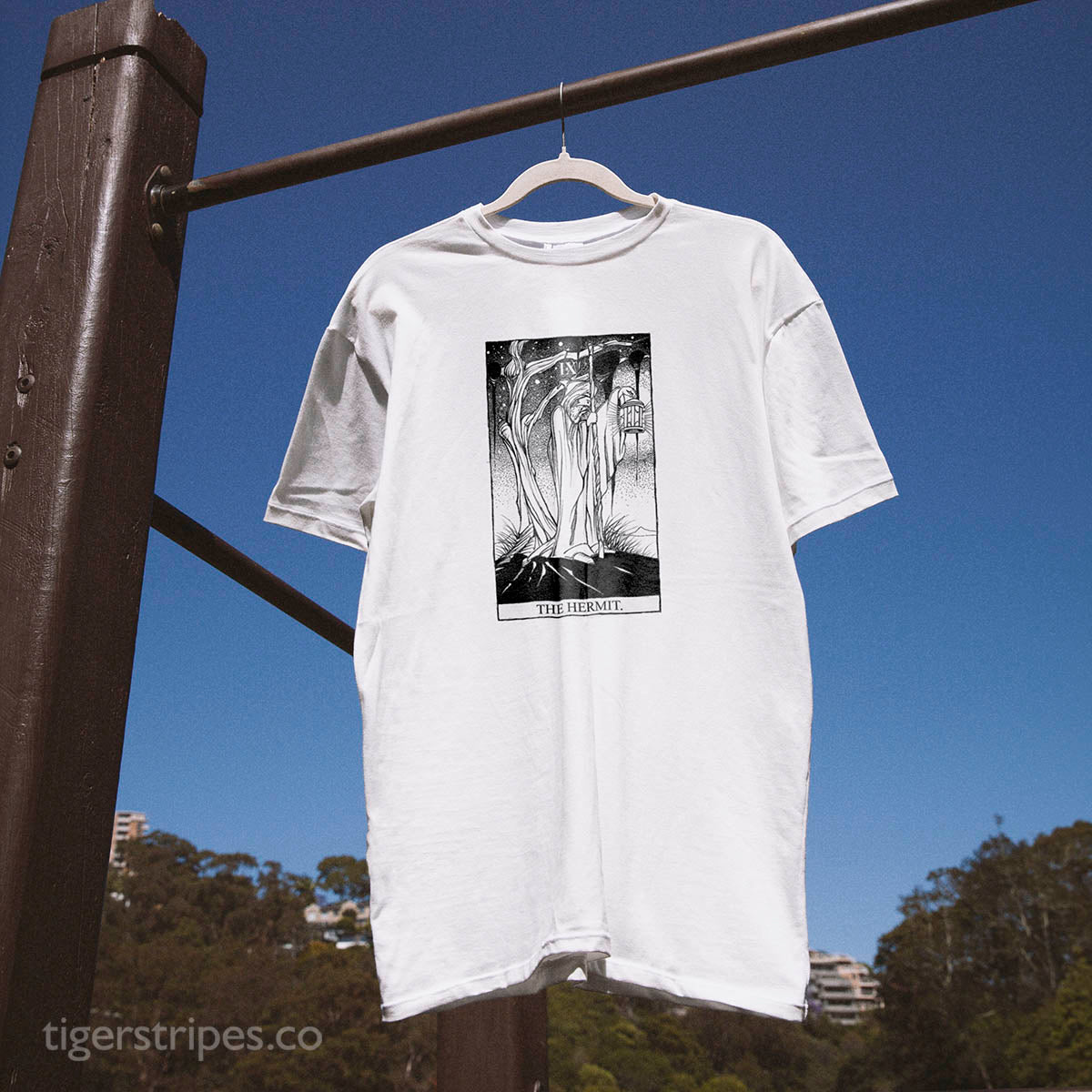 White t-shirt with graphic design hanging on a clothesline against a blue sky
